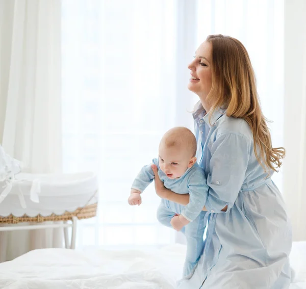 Mãe de meia-idade feliz com seu filho em uma cama — Fotografia de Stock