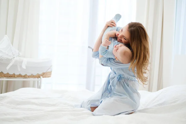 Mãe de meia-idade feliz com seu filho em uma cama — Fotografia de Stock