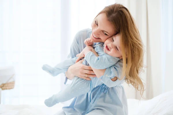 Feliz madre de mediana edad con su hijo en una cama — Foto de Stock