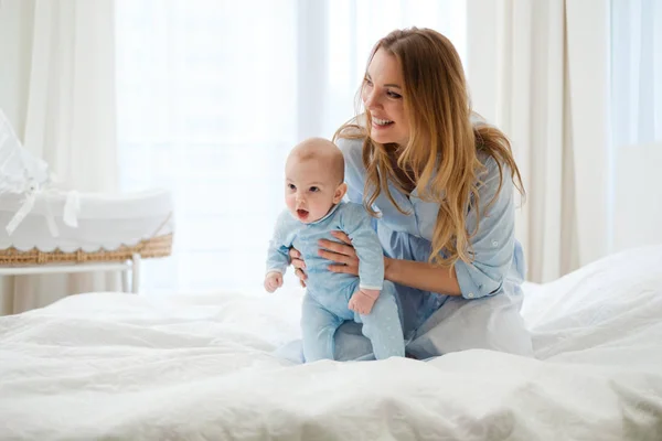 Mãe de meia-idade feliz com seu filho em uma cama — Fotografia de Stock