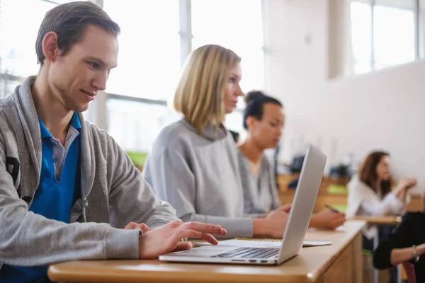 Człowiek z laptopa wśród studentów w audytorium — Zdjęcie stockowe