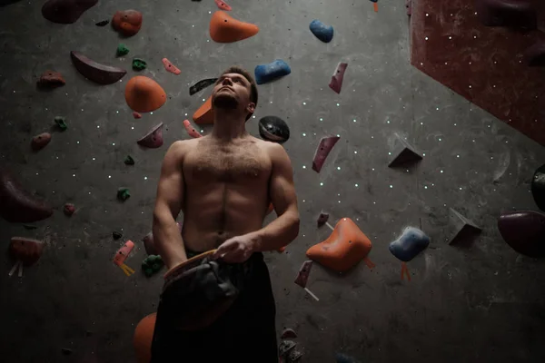 Hombre atlético usando tiza antes de escalar en un gimnasio de bouldering —  Fotos de Stock