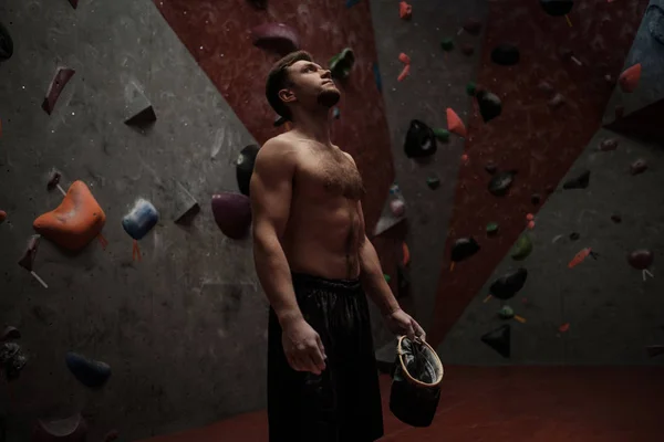 Hombre atlético usando tiza antes de escalar en un gimnasio de bouldering —  Fotos de Stock