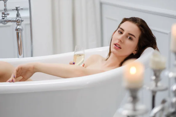 Mujer acostada en un baño con una copa de champán — Foto de Stock