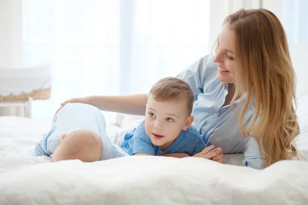 Mãe de meia-idade feliz com seus filhos em uma cama — Fotografia de Stock