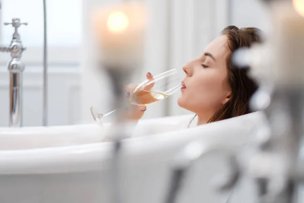 Mulher deitada em um banho com copo de champanhe — Fotografia de Stock