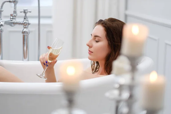 Femme couchée dans un bain avec une coupe de champagne — Photo