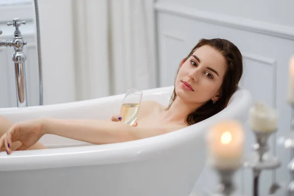 Mulher deitada em um banho com copo de champanhe — Fotografia de Stock