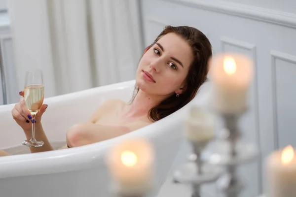 Femme couchée dans un bain avec une coupe de champagne — Photo