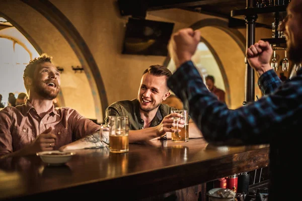 Amigos alegres bebendo cerveja rascunho em um bar — Fotografia de Stock