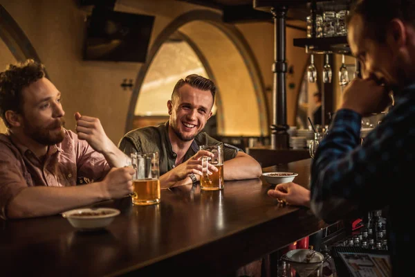 Amigos alegres bebiendo cerveza de barril en un pub —  Fotos de Stock