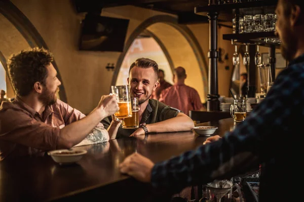 Fröhliche Freunde, die Bier vom Fass in einer Kneipe trinken — Stockfoto