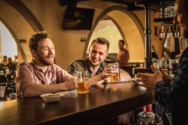 Amici allegri che bevono birra alla spina in un pub — Foto Stock