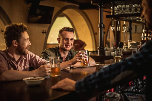 Веселые друзья пьют пиво в пабе — стоковое фото