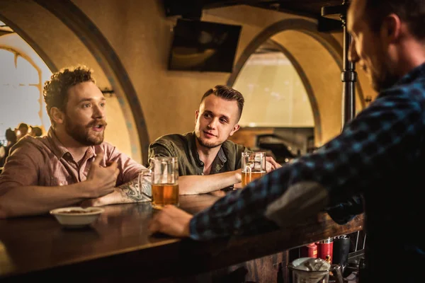 Fröhliche Freunde, die Bier vom Fass in einer Kneipe trinken — Stockfoto