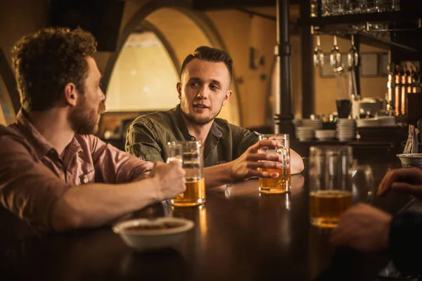 Amigos alegres bebendo cerveja rascunho em um bar — Fotografia de Stock