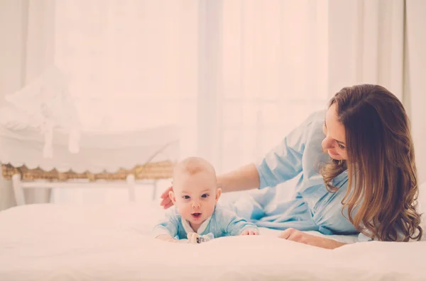 Mãe de meia-idade feliz com seu filho em uma cama — Fotografia de Stock