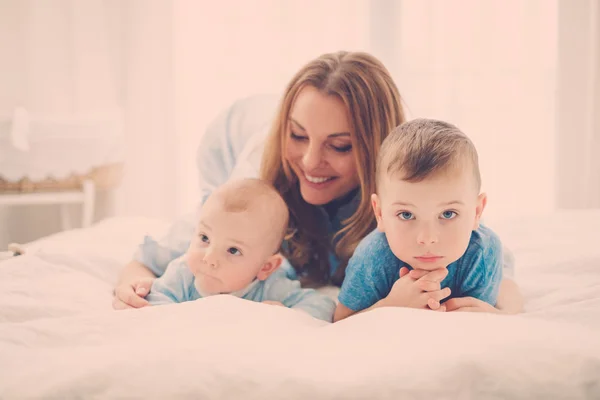 Mãe de meia-idade feliz com seus filhos em uma cama — Fotografia de Stock