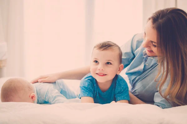 Lycklig mellersta år mamma med sina barn i en säng — Stockfoto