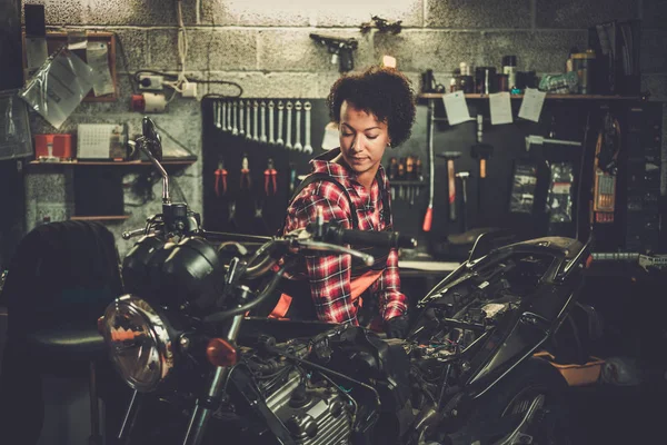 African american woman mechanic repairing a motorcycle in a workshop — Stock Photo, Image