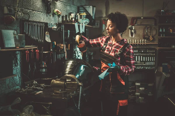 African american woman mechanic polishing motorcycle fuel tank