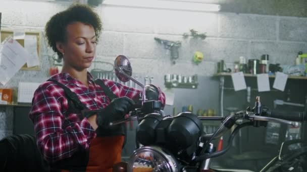 African american woman mechanic repairing a motorcycle in a workshop — Stock Video