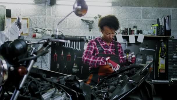 Mécanicien afro-américain réparant une moto dans un atelier — Video