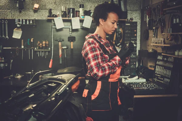 African American kobieta mechanik naprawy motocykla w warsztacie — Zdjęcie stockowe