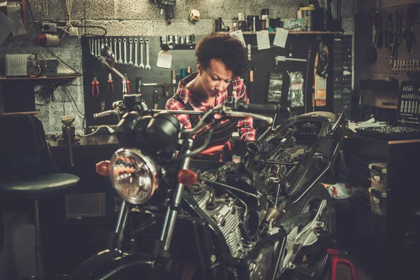 Africano americano mulher mecânico reparando uma motocicleta em uma oficina — Fotografia de Stock