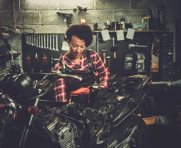 Africano americano mulher mecânico reparando uma motocicleta em uma oficina — Fotografia de Stock