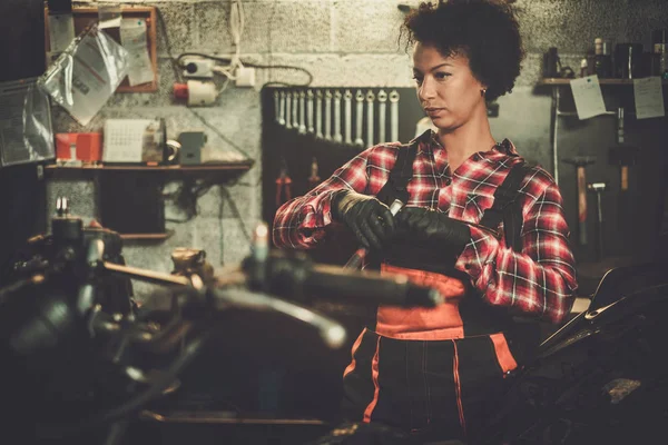 Mujer mecánica afroamericana reparando una motocicleta en un taller —  Fotos de Stock