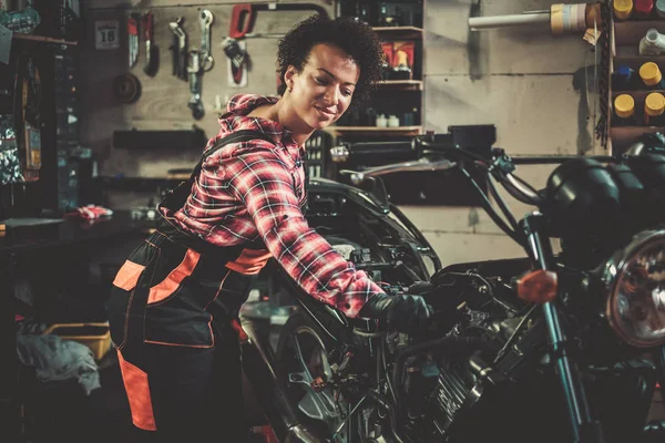 Afrikalı Amerikalı kadın mekanik bir atölyede bir motosiklet tamir — Stok fotoğraf