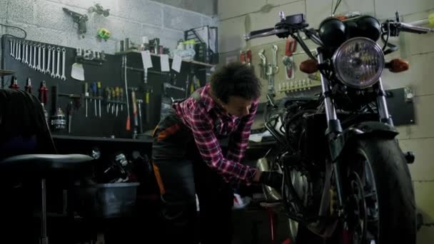 Africano americano mulher mecânico reparando uma motocicleta em uma oficina — Vídeo de Stock