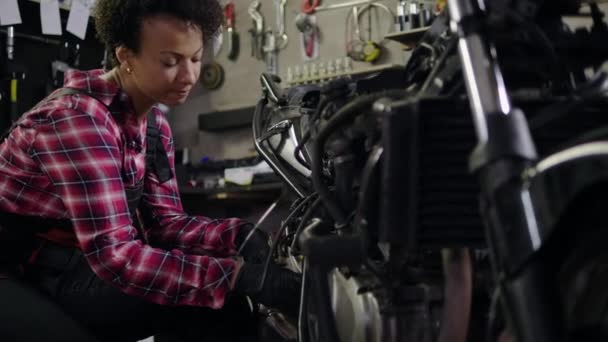 Africano americano mulher mecânico reparando uma motocicleta em uma oficina — Vídeo de Stock