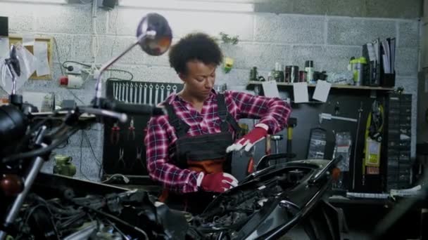 Mécanicien afro-américain réparant une moto dans un atelier — Video