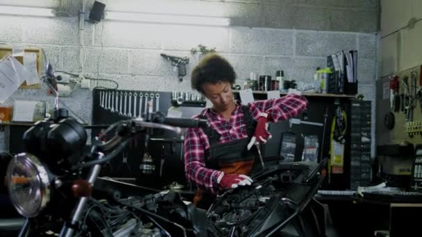 Africano americano mulher mecânico reparando uma motocicleta em uma oficina — Vídeo de Stock