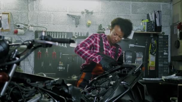 African American kobieta mechanik naprawy motocykla w warsztacie — Wideo stockowe