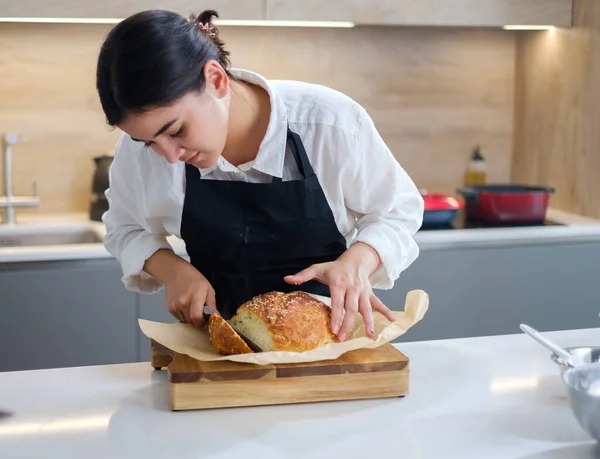 Baker snijdt vers gebakken brood met mes. — Stockfoto