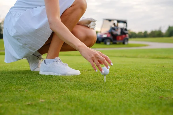 Las manos de la mujer colocan la bola en el pasador de golf . — Foto de Stock