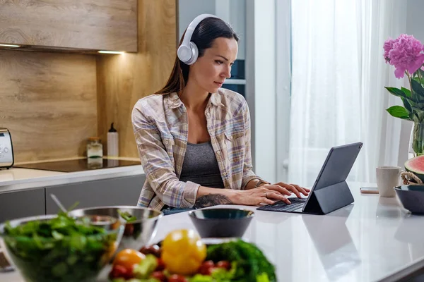 Mulher linda em fones de ouvido brancos Escrever e-mails . — Fotografia de Stock