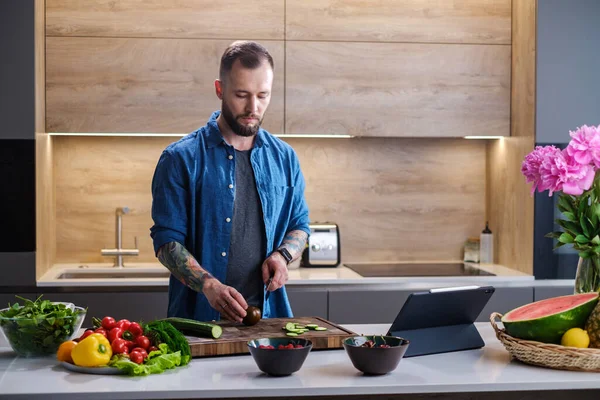 Jonge chef-kok snijdt verse groenten in de keuken . — Stockfoto