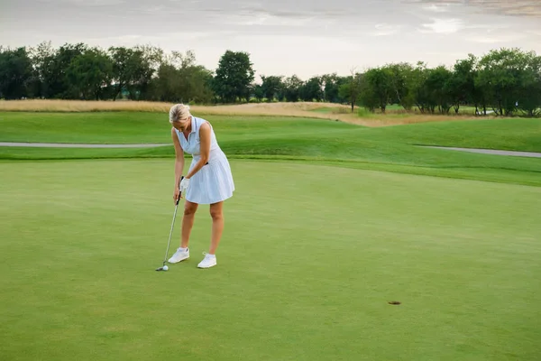 Sportoló nő megpróbál labdát tenni a golf lyukba . — Stock Fotó
