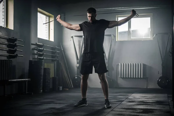 Homme sérieux étirer les bras avec corde de remise en forme . — Photo