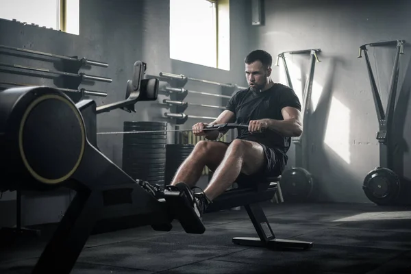 Entraînement masculin fort sérieux de finition avec la machine à ramer . — Photo