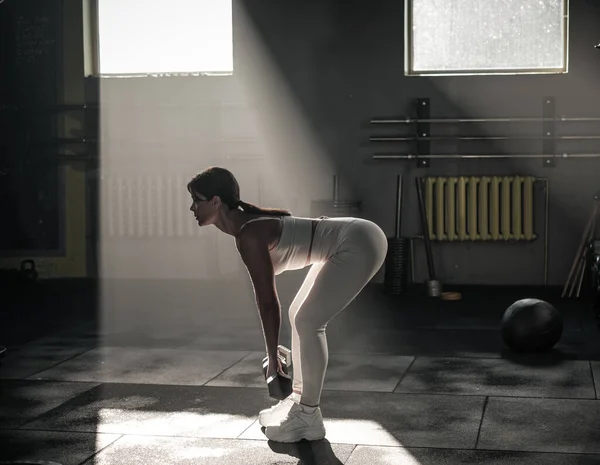 Inclínate hacia adelante con mancuerna en el gimnasio oscuro . — Foto de Stock