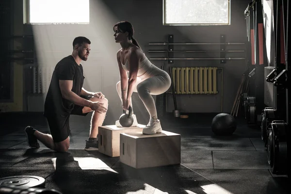Fitness flicka gör knäböj under överinseende av tränare . — Stockfoto