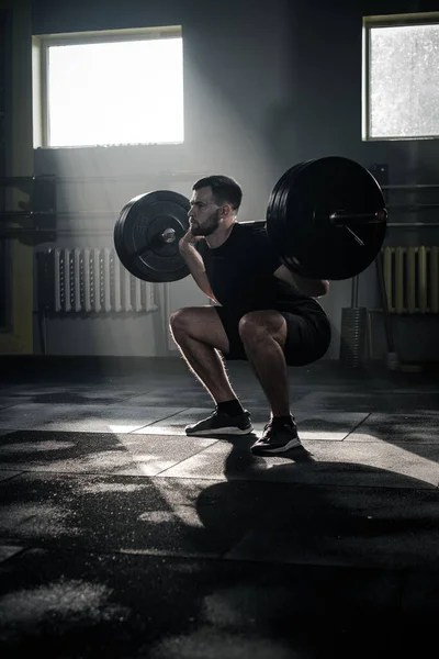 Concentrato maschio fare squat esercizio con bilanciere . — Foto Stock