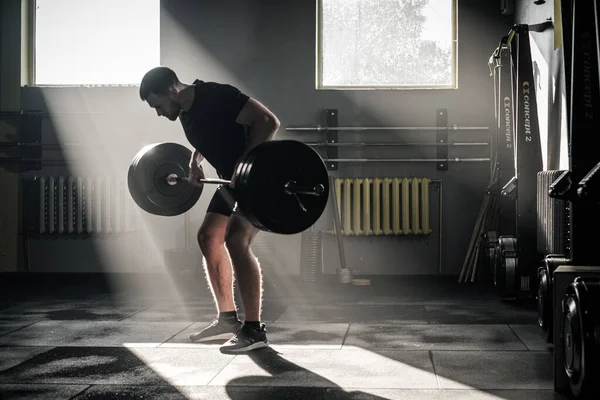 Gespierde man maken harde armen workout met lange halter . — Stockfoto