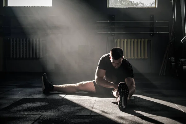 Sportman Strek voorzichtig zijn benen . — Stockfoto