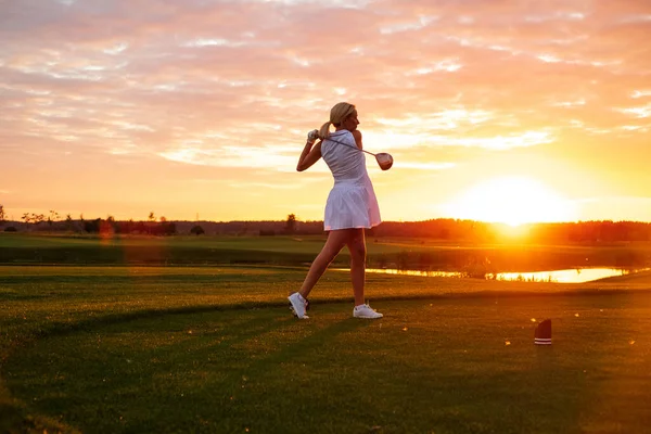 Professionell spelare kvinna spela golf med solnedgång bakgrund . — Stockfoto